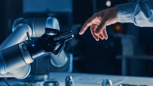 Menschliche und robotische Hand als Symbol für Open Innovation, Zusammenarbeit und digitale Transformation in der Fertigungsindustrie